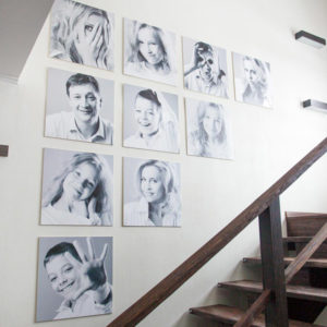 семейные фотографии одинакового размера на стене лестницы