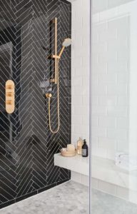 стена в ванной отделана черной плиткой с укладкой елочкой